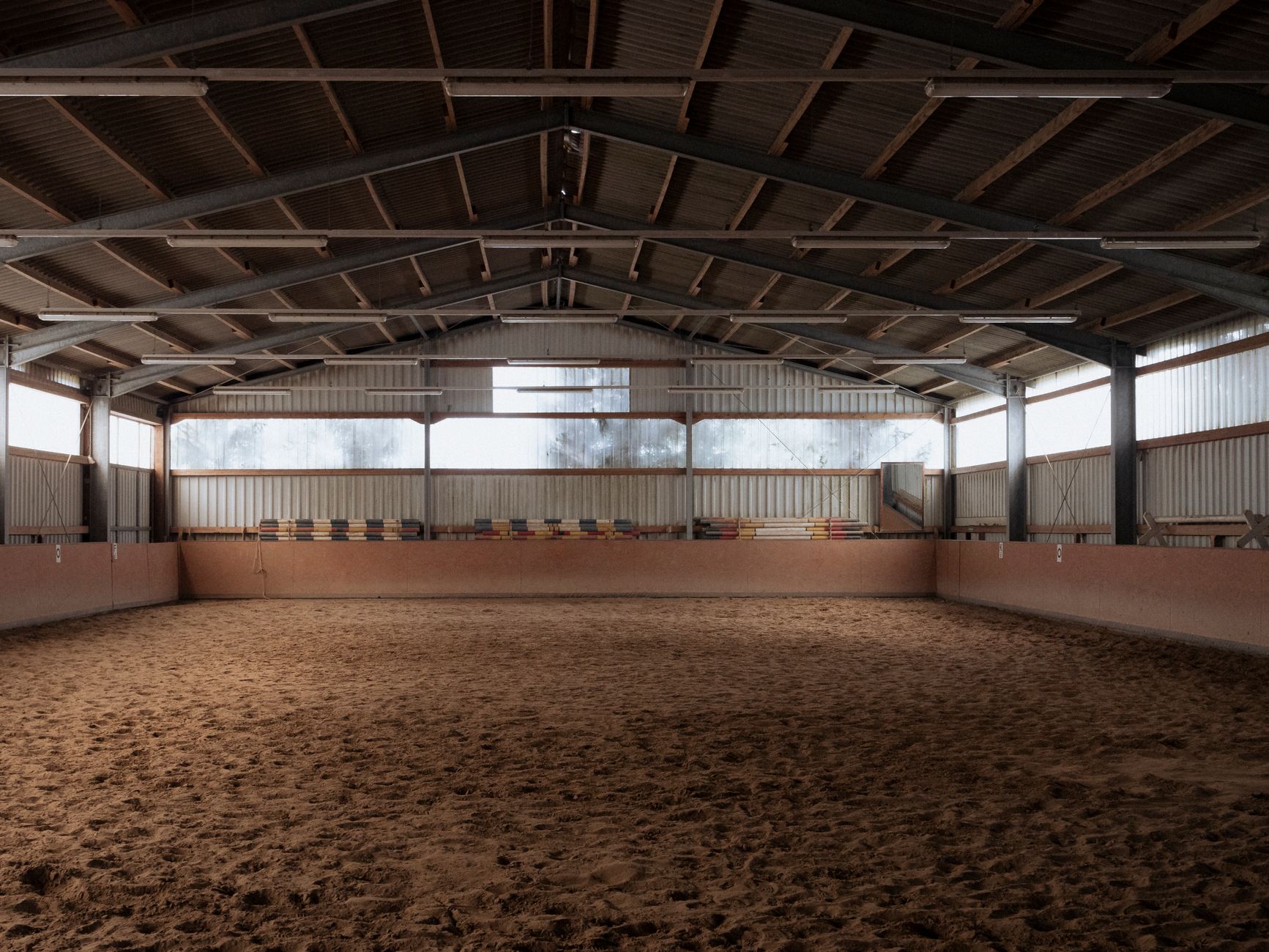 Indoor riding arena with sandy floor and natural light
