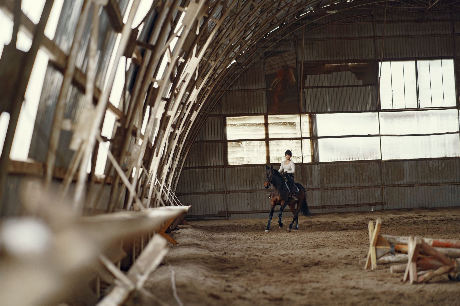 Woman rides a horse in a rustic indoor riding arena