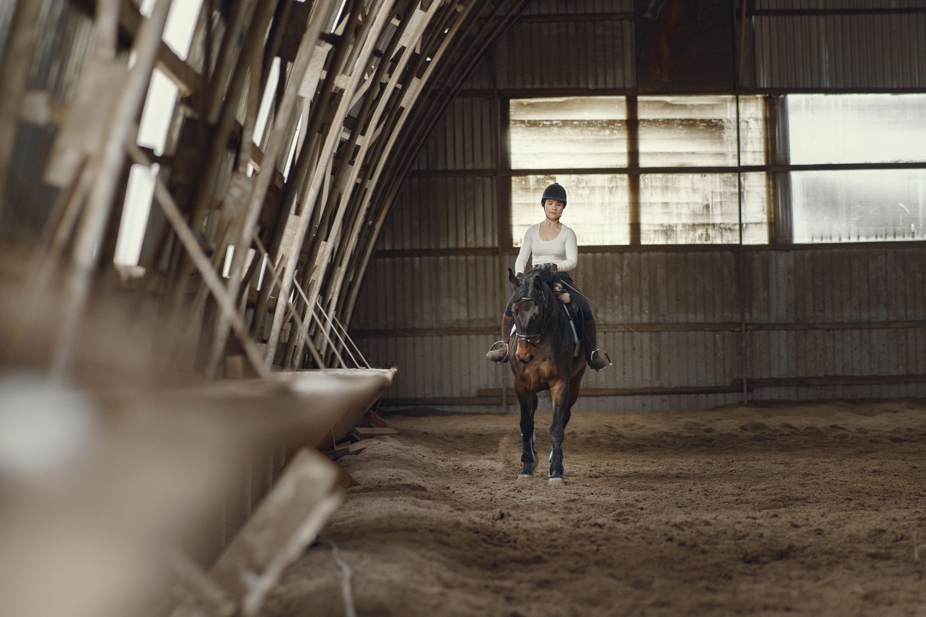Young woman riding a horse inside a barn setting